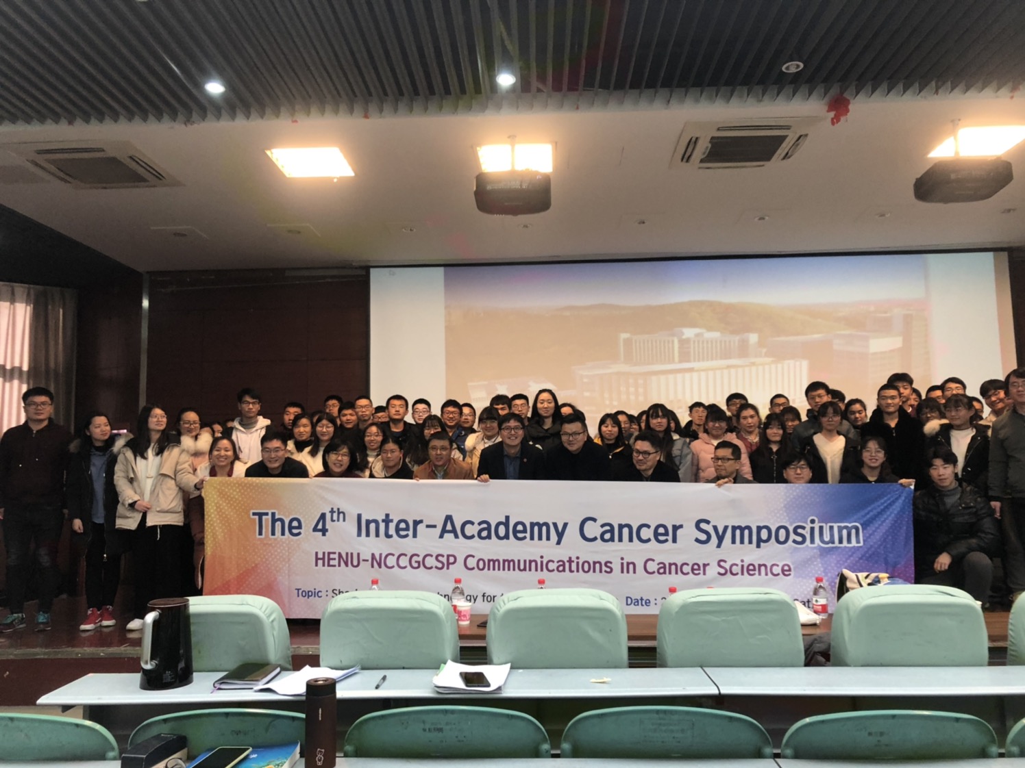 A photo of professors including Park Jong-bae, Dean of Graduate School, Lee Ho, Dean of Cancer and Biomedical Sciences, Professor Yun Geum-ryong, and students of Henan University in China holding a symposium banner at the 4th Inter Academy Cancer Symposium